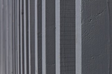 Close-up photograph of a board and batten style wall or fence with vertical planks painted a uniform gray color, Pitkäsilta, Helsinki, Finland.