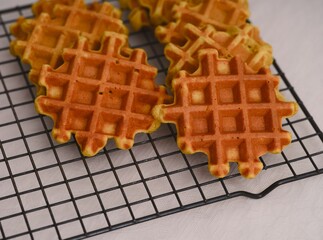 Freshly baked golden waffles cooling on a wire rack.