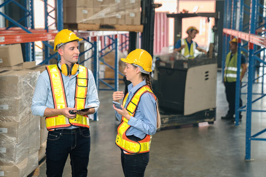Caucasian man, woman warehouse supervisor discuss and use tablet check package with forklift driver worker load box on shelf, product distribution inventory management,Logistics shipping business plan