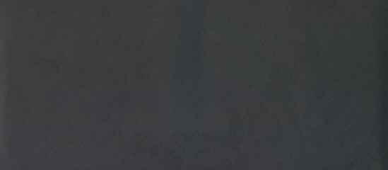 Black rough surface of old paper or cardboard, background, texture. Backdrop of black paper surface with elements of aging. Old and shabby paper piece. Ancient wall in ashen color. Black paper surface