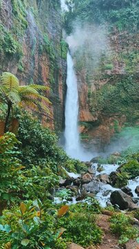 Koban Kapas Biru is a waterfall in the tropical jungles of East Java, descending from a high cliff into a lush green canyon surrounded by tropical forests with vibrant vegetation.Lumajang River. 4К