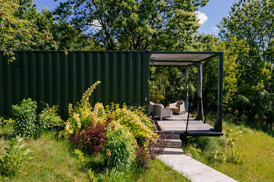 Modern container home with outdoor seating in a lush green landscape