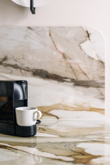 Elegant modern kitchen with marble countertop and coffee cup on counter