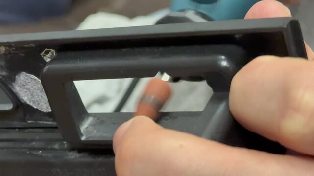 Craftsman hands processing material edge with a high speed rotary dremel tool in a workshop. Electric rotary tool grinding a smooth surface edge close up. 