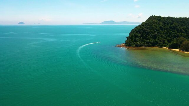 Aerial view of a small tropical island located just off the coast of Pantai Bukit Keluang in Besut, Terengganu. The island is covered in dense green forest and surrounded by vibrant turquoise waters.