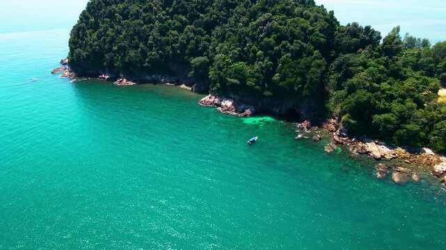 Aerial view of a small tropical island located just off the coast of Pantai Bukit Keluang in Besut, Terengganu. The island is covered in dense green forest and surrounded by vibrant turquoise waters.