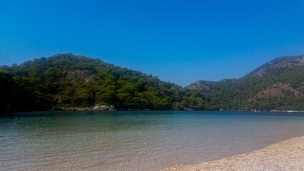 Sandy Beach and Calm Waters — Green Hills, Blue Sky, and Coastal Stillness in Oldöniz, Turkey