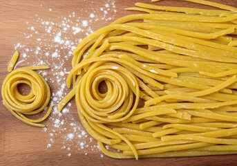 Freshly made pasta noodles and flour dusting on a wooden surface, food preparation ingredients for italian cuisine