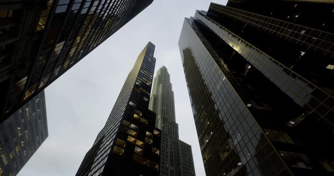 Concrete giants pierce the overcast sky as light glimmers off their glass facades. Skyscrapers stand tall amidst the hustle and bustle of urban life, creating a modern marvel of architecture.