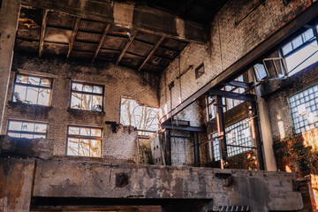 Abandoned industrial building interior with broken windows, exposed brick walls, and sunlight streaming through, showcasing urban decay and historical architecture