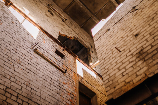 Abandoned industrial building with exposed brick walls and natural light streaming through broken windows, creating a dramatic atmosphere of decay and history - Powered by Adobe