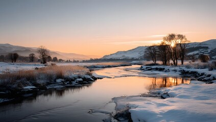 Beautiful winter sunrise over a serene river with snow covered banks and trees reflecting the golden sky