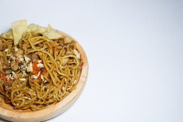 A bowl of spicy fried noodles with wonton crackers in a bowl, isolated on a white background with a wooden plate and traditional chopsticks