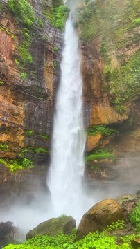 Koban Kapas Biru is a waterfall in the tropical jungles of East Java, descending from a high cliff into a lush green canyon surrounded by tropical forests with vibrant vegetation.Lumajang River. 4К