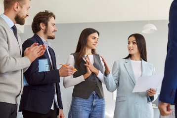 Businesswoman leading a team meeting and presentation for a group of colleagues in an office setting. Organized work environment emphasizes effective conversation and collaboration.