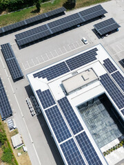 Fototapeta premium Aerial view of building with solar panels on a roof and parking space with solar canopies
