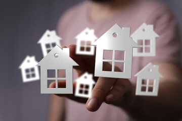 A creative composition with 3D rendered home symbols in the air above a hand, representing ideas of real estate and property ownership. Great vi