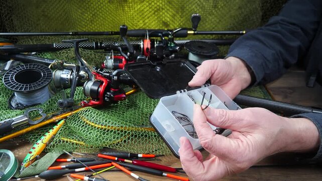 A fisherman assembles and checks his tackle before fishing. Close-up of his hands.