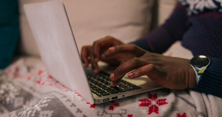 This close-up shows the hands of a young man typing on a laptop keyboard. He concentrates on his...