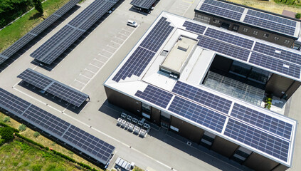 Aerial view of building with solar panels on a roof and parking space with solar canopies