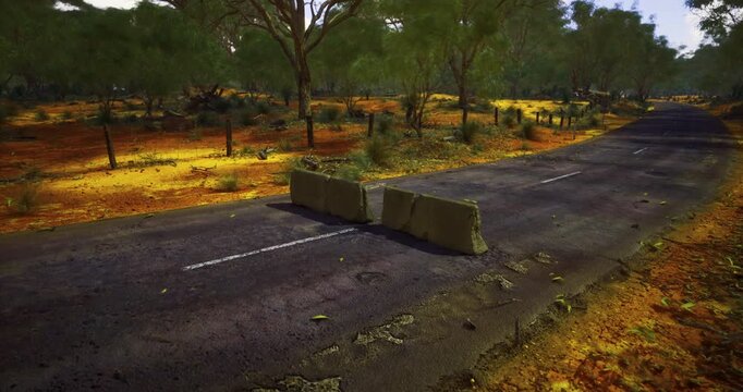 In the heart of a sunbathed outback, a barricade interrupts a quiet road, surrounded by lush trees and golden earth. Nature coexists with the aftermath of human intervention, creating a still moment.