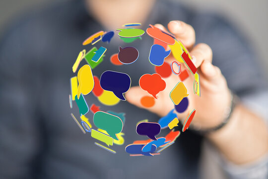 Hand holding globe of colorful speech bubbles represents global communication and social media engagement. Networking and connection concept.