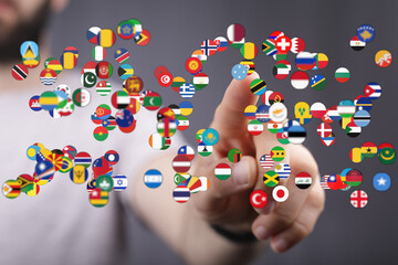 A hand interacts with a display of international flags representing global awareness, travel, and international relations. Symbolic of unity, co