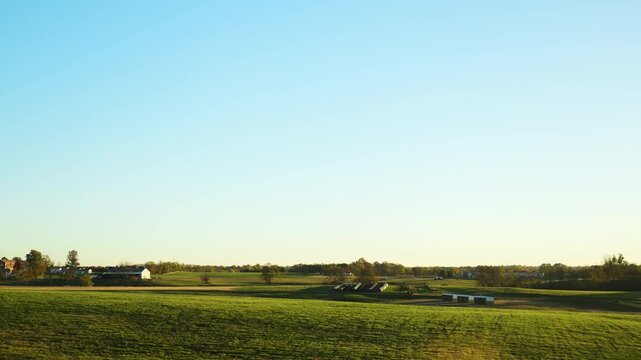 POV of driving at a sideroad of highway surrounded by vibrant autumn trees under a clear blue sky. Cars travel along the road as fall foliage lines both sides,