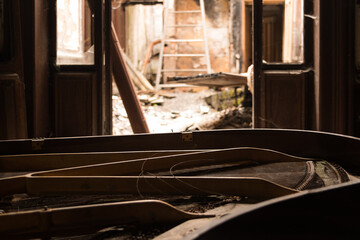 Abandoned grand piano in a decaying villa with exposed strings and doorway light