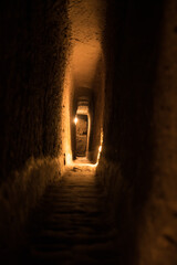 Ancient narrow stone corridor - dimly lit subterranean passage with warm golden glow