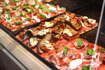 Authentic Italian pizza in a restaurant display window in Rome, Italy.  Different type of traditional Roman styple pizza . 