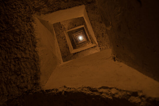 Square Lightwell Looking Up - Warm Textured Stone Shaft with Concentric Squares and Dramatic Vertical Perspective