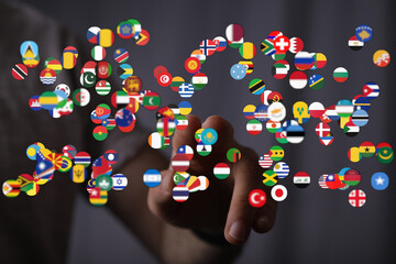 A hand pointing towards a collection of flags representing different countries, symbolizing global connectivity, international relations, and th