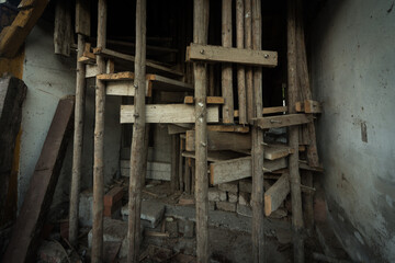 Makeshift wooden scaffolding and narrow staircase inside a dilapidated building
