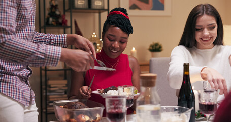 Students celebrate a friend's birthday. A girl with dark hair in a white sweater and a multi-ethnic...