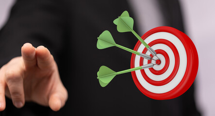 Image of a hand pointing at a target with three darts in the bullseye, symbolizing success,...