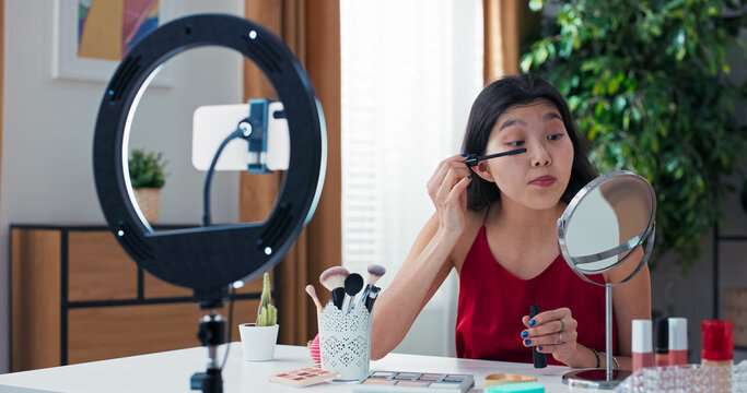 The influencer applies mascara during a live video, giving her audience tips on how to lift lashes and avoid clumps. - Powered by Adobe