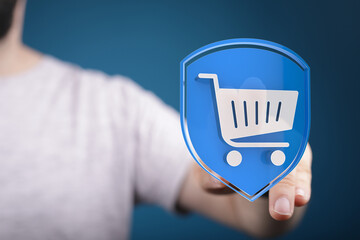 Secure online shopping, e-commerce concept. Hand holding digital shield with shopping cart icon....