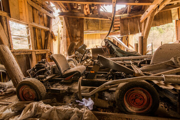 Sunlit Derelict Car Chassis in Weathered Barn Interior - Rustic Automotive Decay