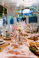 Elegant table setting with pink candles and roses for a festive dinner, soft pastel decor