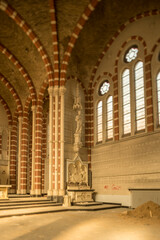 Fototapeta premium Sunlit abandoned church interior with striped brick arches, ornate altar and stained glass
