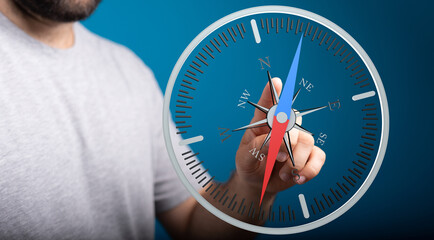 Close-up of a person's hand holding a compass. Symbolizes direction, guidance, and the pursuit of...