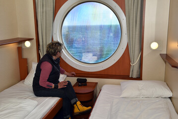 Frau schaut aus ihrer Kabine auf das Meer 