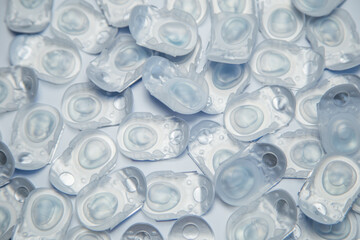 Close-up: many daily contact lenses in a disposable protective case, in which clear lenses float, lying on a white background. The concept of ophthalmology, vision correction, eye care. High quality