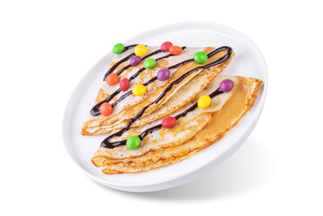 Fried crepes with peanut butter filling and chocolate and multicolored candies topping in the form of Christmas tree on a white isolated background