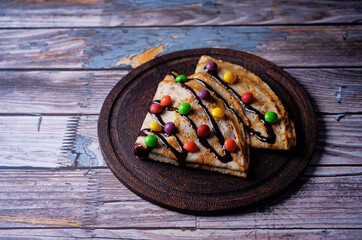 Fried crepes with peanut butter filling and chocolate and multicolored candies topping in the form of Christmas tree