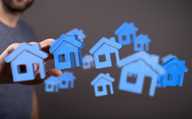 Conceptual image of hand holding miniature blue houses, symbolizing real estate, investment, and home ownership. Perfect for illustrating proper
