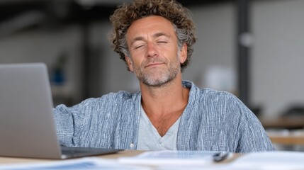 Person leaning back comfortably with eyes closed while sitting at a desk with a laptop