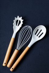 Modern White Kitchen Utensils with Wooden Handles on Dark Background