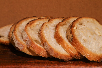 Freshly cut sourdough slices display a crisp crust and soft interior, creating a comforting artisanal scene. A homely culinary mood emerges from the combination of rustic bread and dark wood grain.